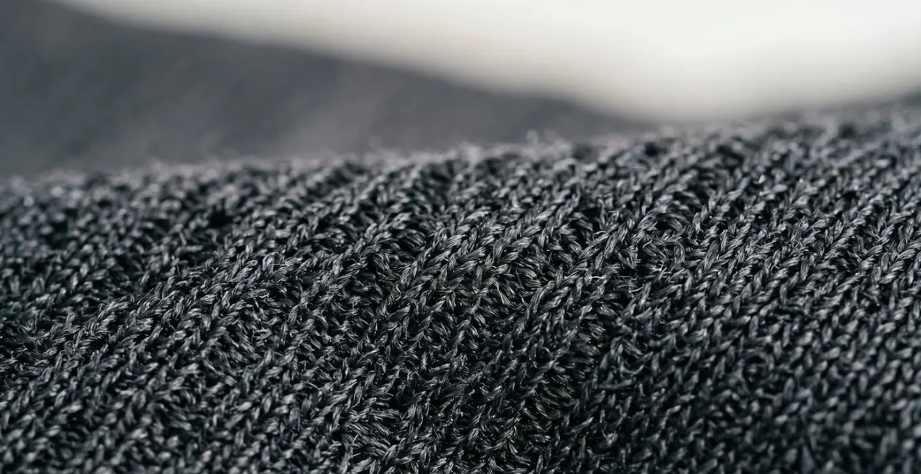 Dettaglio macro ravvicinato di tessuto tecnico sportivo che mostra la trama e la texture delle fibre traspiranti