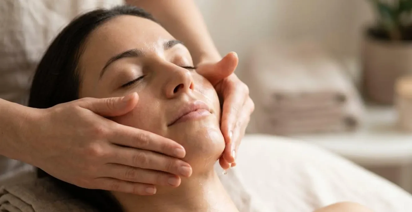 Mani femminili che massaggiano delicatamente il viso con movimenti circolari durante la routine di detersione