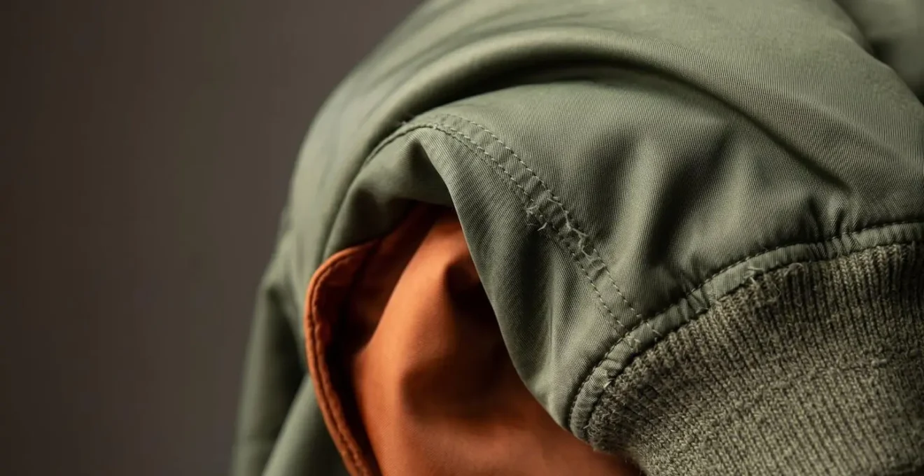 Dettaglio macro di tessuto bomber con drappeggio che mostra texture e volume controllato