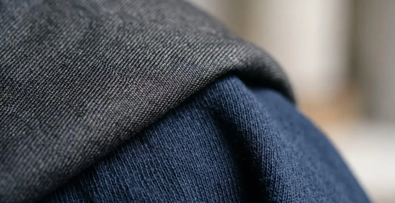 Composizione che illustra il concetto di sprezzatura milanese attraverso contrasti tattili tra tessuti streetwear e sartoriali
