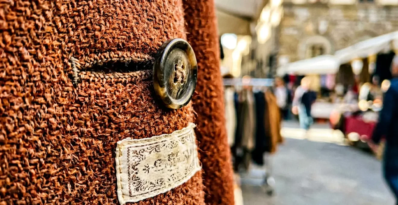 Dettaglio ravvicinato di cappotto di lana vintage anni '80 Made in Italy appeso in un mercatino italiano