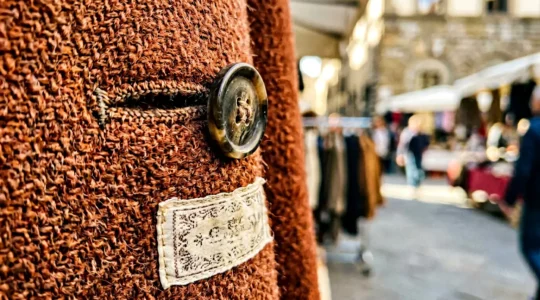 Dettaglio ravvicinato di cappotto di lana vintage anni '80 Made in Italy appeso in un mercatino italiano